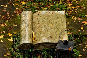 tombstone in shape of a book in a graveyard