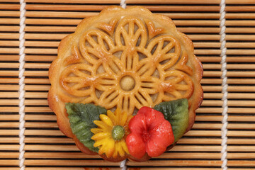 Colorful flower decorated mooncake Chinese mid autumn festival on bamboo food mat background