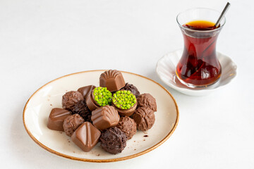 Variety of luxury chocolates on a white background. Along with a cup of tea