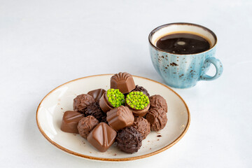 Variety of luxury chocolates on a white background. Along with a cup of coffee