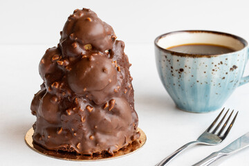 Profiterole tower cake on a white background. Along with a cup of coffee