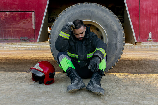 Sad fireman sitting near truck