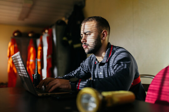 Thoughtful man using laptop at workplace