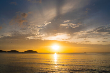 Landscape empty beach island during Sunset.Red purple orange blue pink sunsets over sea and Burning sky and shining golden waves.Sun over sea silhouette paradise island.