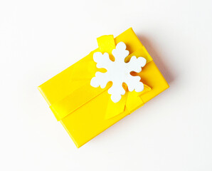 Yellow Christmas Gift Box with White Snowflake Decoration on a light background