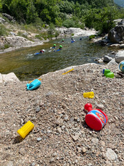 Peoples canyoning in Chassezac river with in a foreground children toys on the beach, Lozere, France