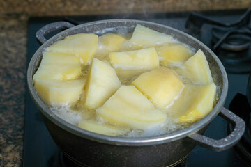 Close-up of the pot is on the stove, potatoes are cooking in it, the water is already boiling. Home cooking