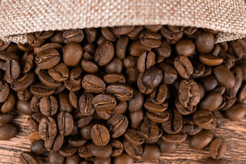 Black coffee foil packaging bag on wooden table top view. Spilled beans flat lay concept. Room for text...