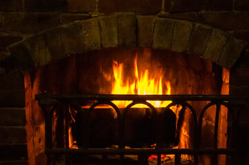 Fireplace with burning logs. The fireplace creates coziness in the house.