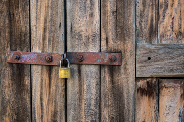 Detail of the old wooden door with rusty fittings and a padlock