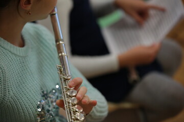 Teenage girl playing the flute in a music lesson at school hand valve close-up selective focus