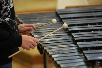 Person playing percussion stick hammer in hand hits black old wooden xylophone keys close-up...