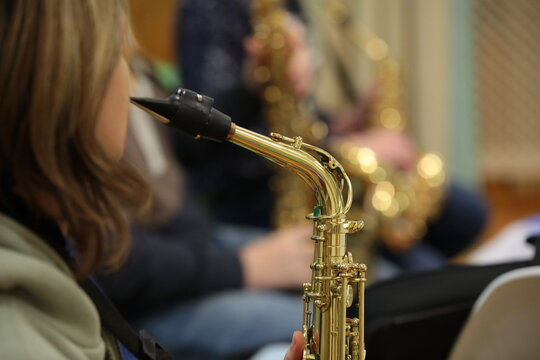 Girl playing the saxophone in the orchestra background image selective focus