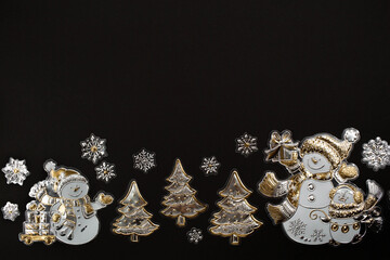 Banner. Happy New Year and Merry Christmas 2022. Snowmen with gifts, spruce and snowflakes made of gold and silver foil on a black background. Flat lay.