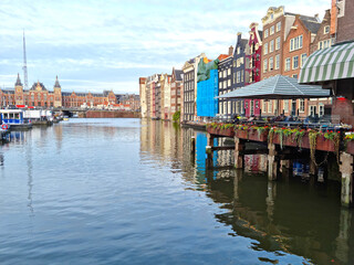 Fototapeta premium Houses by a canal and the central station in the background, Amsterdam, The Netherlands