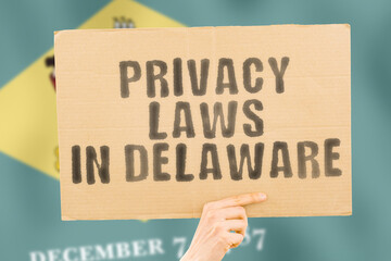 The phrase " Privacy laws in Delaware " on a banner in men's hand with blurred Finnish flag on the background. Private. Client. Market. Info. Information. Identify. Data. Security. Technology