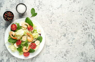 Fresh seafood salad. Grilled shrimp, fresh vegetable salad and egg. Fried shrimps. Healthy food on stone background with copy space for your text