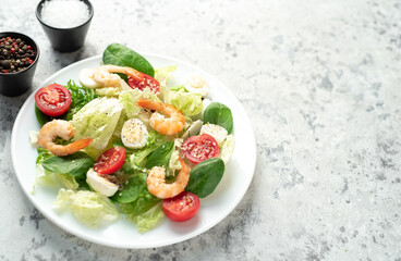Fresh seafood salad. Grilled shrimp, fresh vegetable salad and egg. Fried shrimps. Healthy food on stone background with copy space for your text