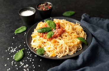 Classic Italian spaghetti pasta with tomato sauce, parmesan cheese and spinach on a plate on a stone background