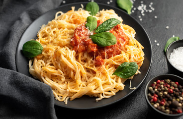 Classic Italian spaghetti pasta with tomato sauce, parmesan cheese and spinach on a plate on a stone background
