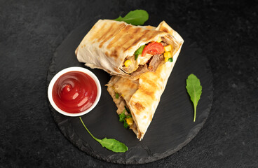 Burrito wraps with grilled beef and vegetables on a stone background. Mexican food.