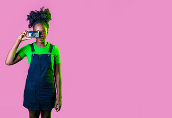 Young black woman taking photograph using vintage camera smiling happy and positive isolated advertising copy space background