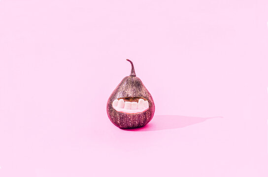 A dark green pumpkin with white teeths on pastel pink background. Scary surreal Halloween concept. Banner or party invitation.