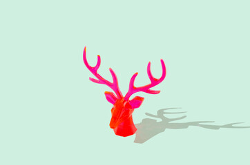 Neon red reindeer head isolated on pastel green background. Creative Christmas and New Year celebration concept. Minimal festive banner with copy space.