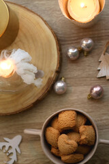 Bowl of cinnamon cookies, lit candles and various Christmas decorations on the table. Flat lay.