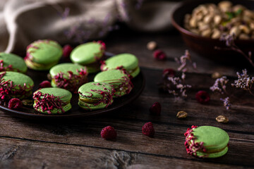 pistachio macarons on wooden background 
with raspberries