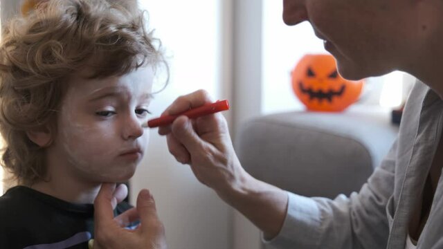Close-up of Mother painting her son on halloween holiday