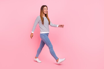 Full size photo of young optimistic brown hairdo lady go wear shirt jeans sneakers isolated on pink background