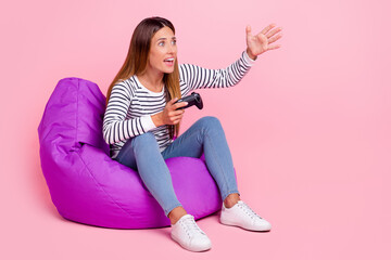 Photo of shocked impressed woman dressed pullover sitting bean bag playstation looking empty space isolated pink color background