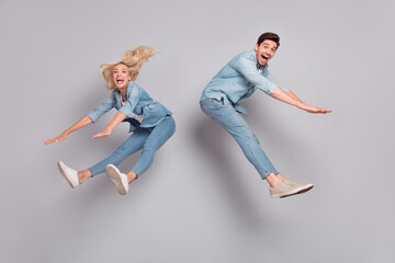 Full length body size view of attractive friends friendship jumping having fun fooling isolated over grey pastel color background