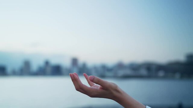都市の前で手をかざす女性