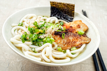 Traditional Japanese udon fish ramen soup with noodles and bonito flakes served as close-up in a design bowl