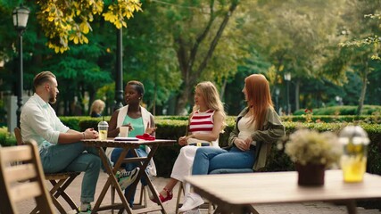 Summer time multiracial friends black woman and one guy have a meeting in the park at cafe they discussing together and enjoy the meeting