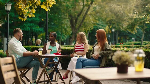Summer time multiracial friends black woman and one guy have a meeting in the park at cafe they discussing together and enjoy the meeting