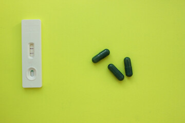 positive pregnancy test and pills on a yellow background. Vitamins. Motherhood, children,...