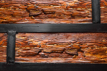 Texture close-up photo of varnished wood logs with metal frame holding it.