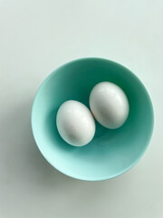 Top view of two eggs in the blue bowl on white background. 