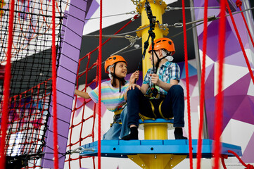 Fototapeta na wymiar Two children in helmets climb on tightropes