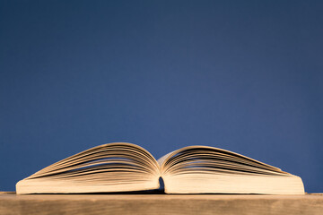 Open book on blue background, close up