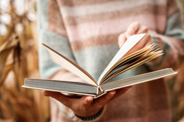 Open book in female hand. Woman reading book outdoors