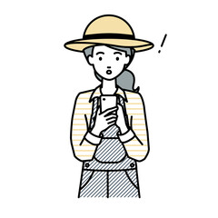 立ってスマートフォンを操作して何かに気づいて驚いた農家の女性