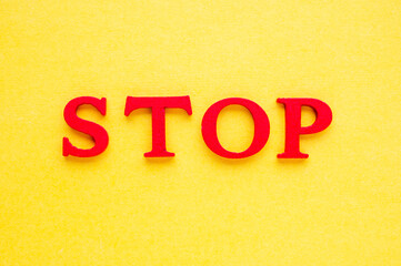 Stop word with red wooden letters over yellow background
