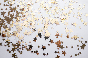 Gold stars shiny glitter on a white background, selective focus