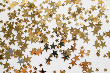 Gold stars shiny glitter on a white background, selective focus