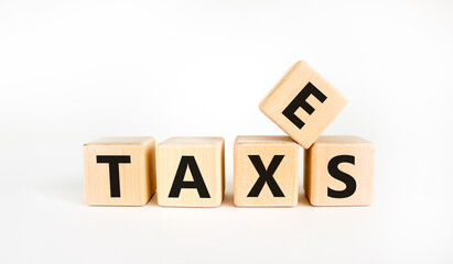 Taxes symbol. The concept word 'taxes' on wooden cubes on a beautiful white table. White background. Business and taxes concept. Copy space.