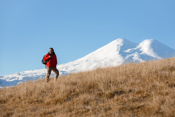 Adult male traveler with a backpack on the background of a landscape with a mountain. Karachay Cherkessia, Elbrus.